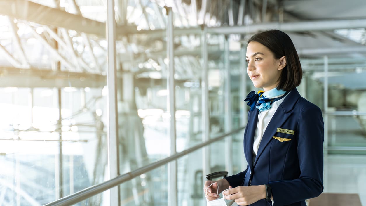 A female air hostess is standing in an airport.