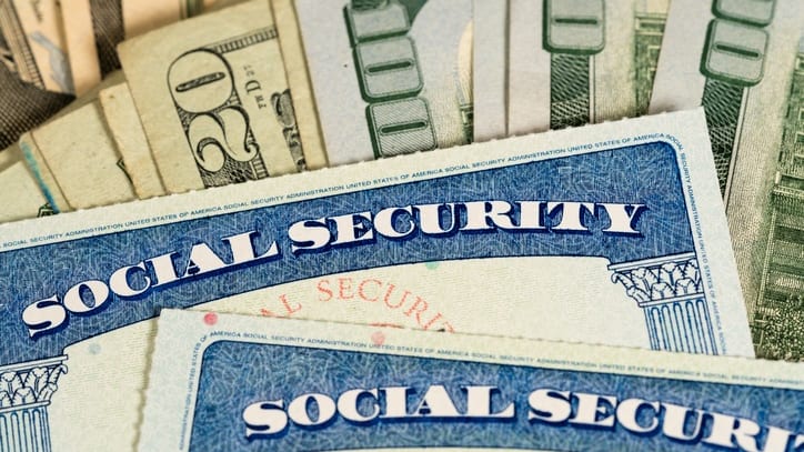 A stack of social security cards on a pile of money.