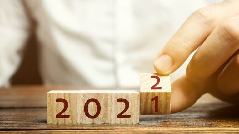A person is holding a wooden block with the number 2021 on it.