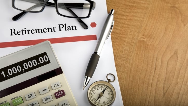 Retirement plan with glasses and a calculator on a wooden table.