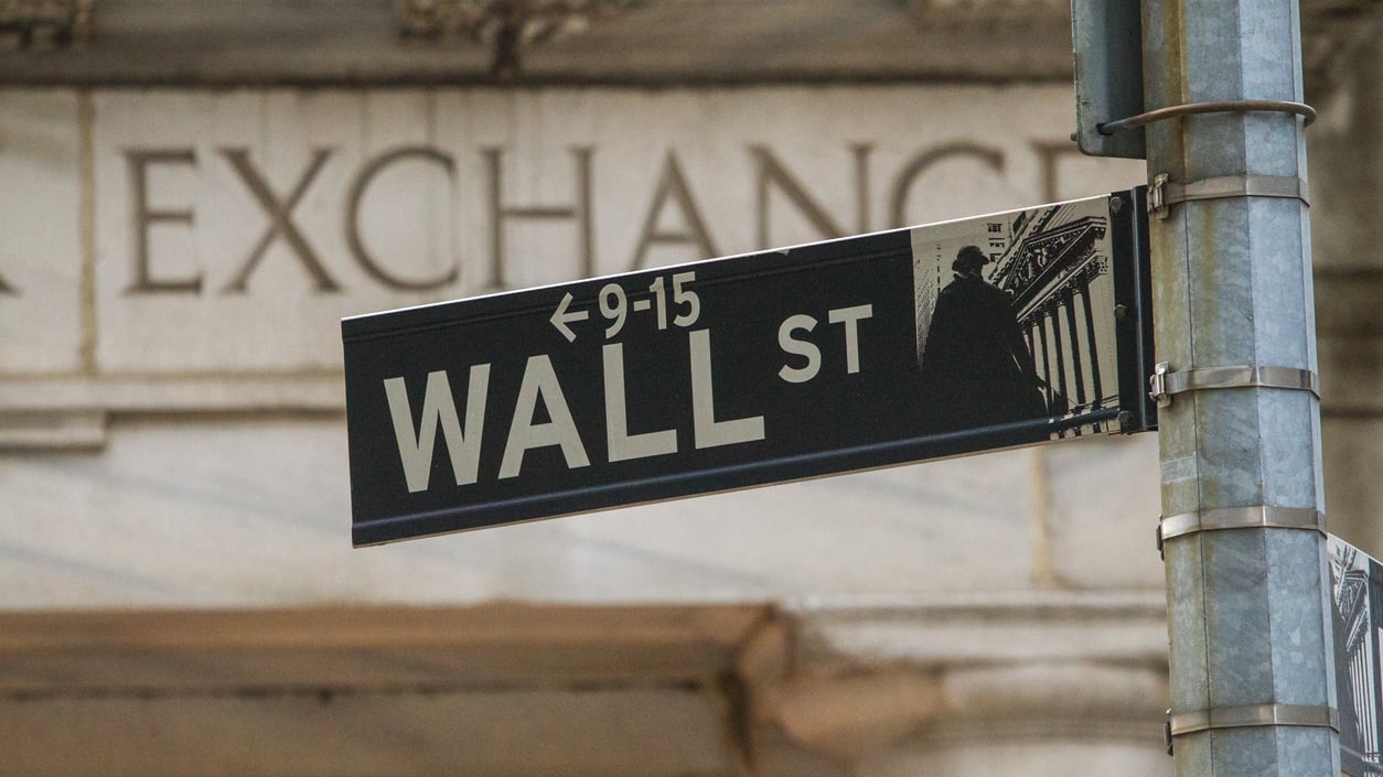 A wall street sign in front of a building.