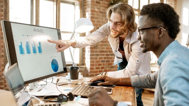 Two businessmen pointing at a graph on a computer screen.