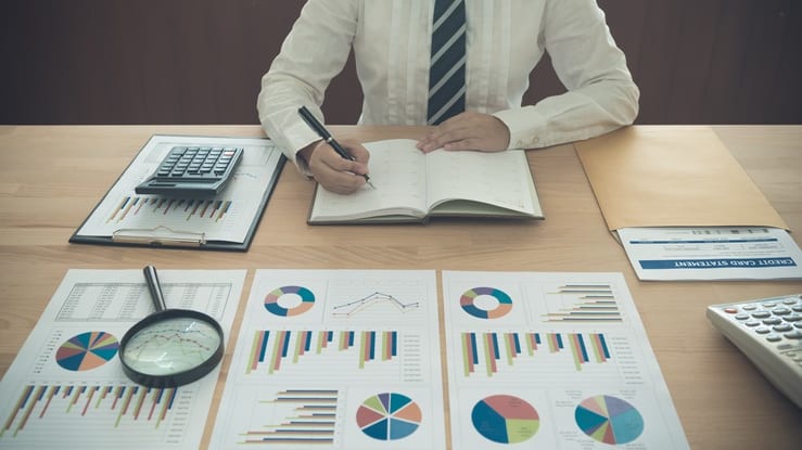 A businessman sitting at a desk with papers and graphs.