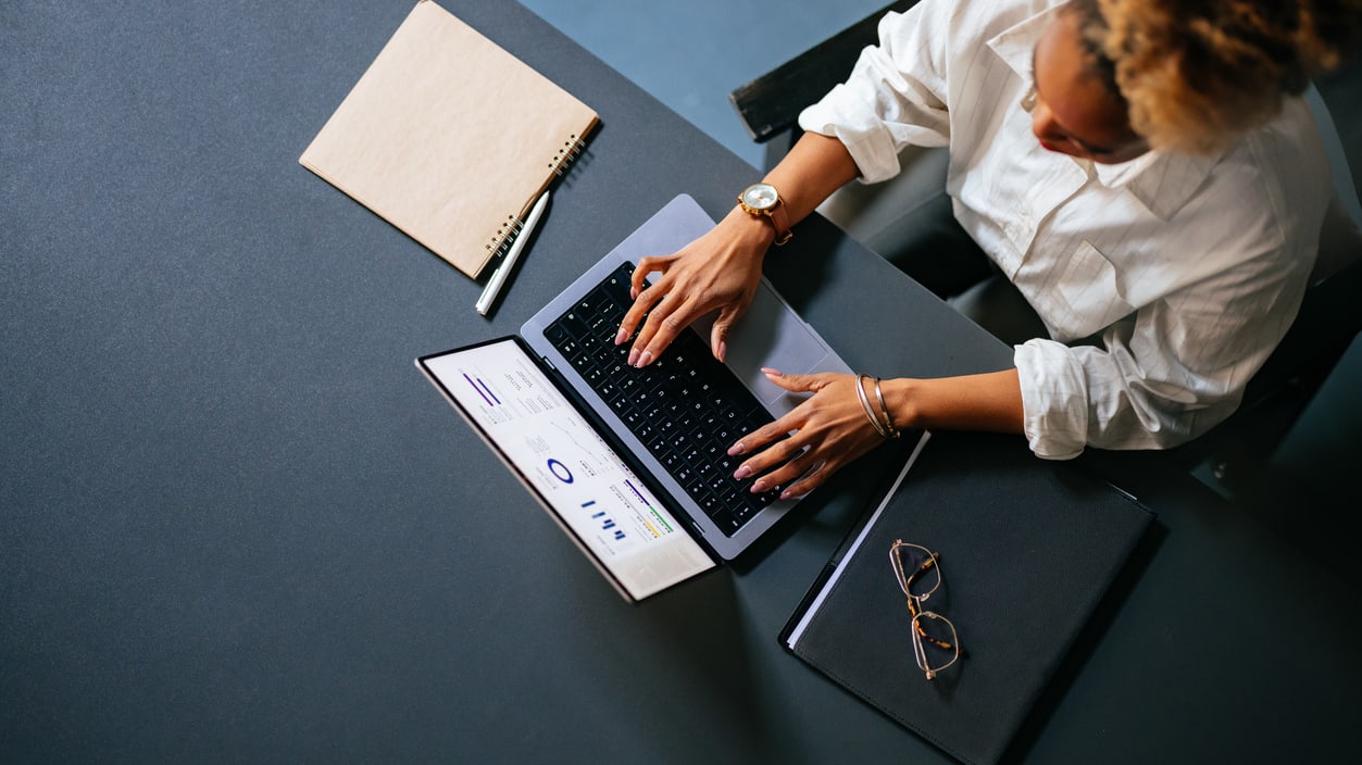 A woman working on a laptop at a desk.