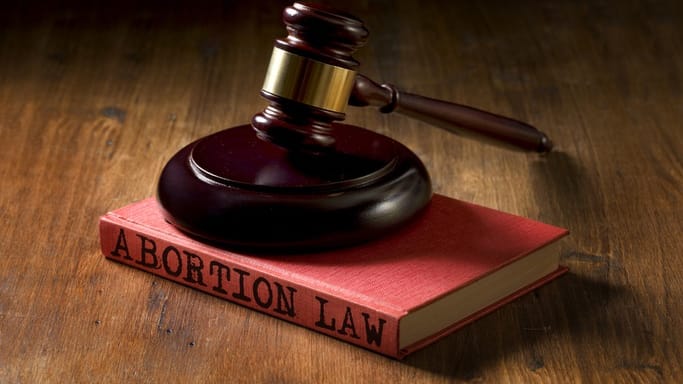 A gavel sits on top of a book with the word abortion law.