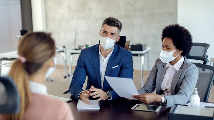 A group of business people wearing face masks at a meeting.
