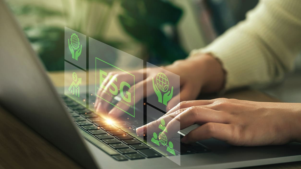 A woman is typing on a laptop with green icons on it.