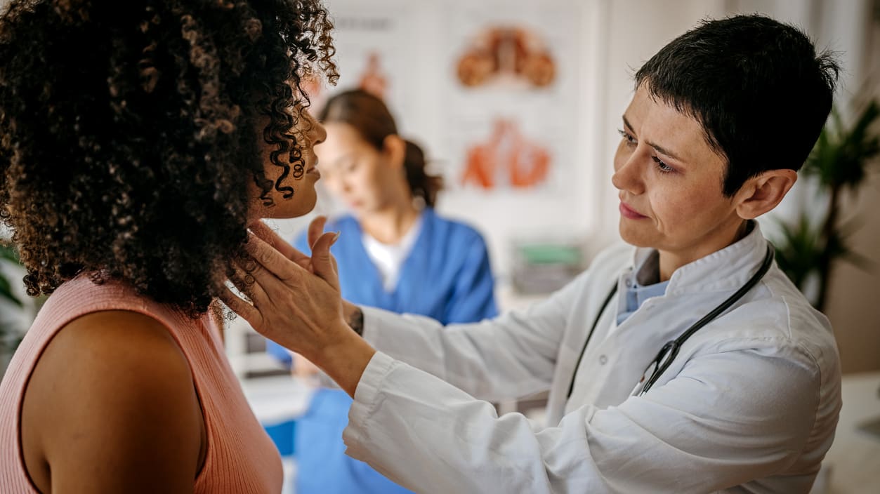 A doctor is examining a woman's neck.