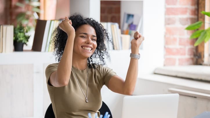 Happy african american woman celebrating success in the office stock photo.