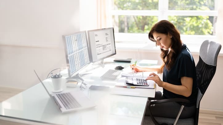 A woman is working at her desk in front of a window.