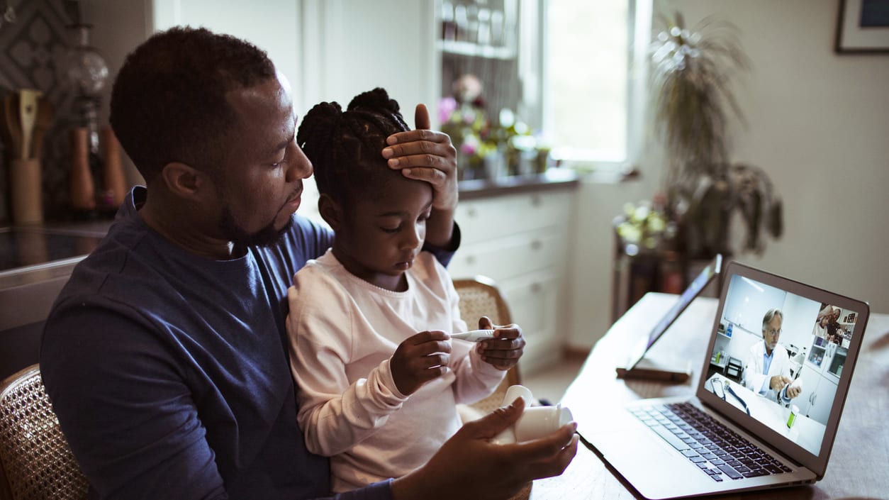 A man and his daughter are watching a video on a laptop.