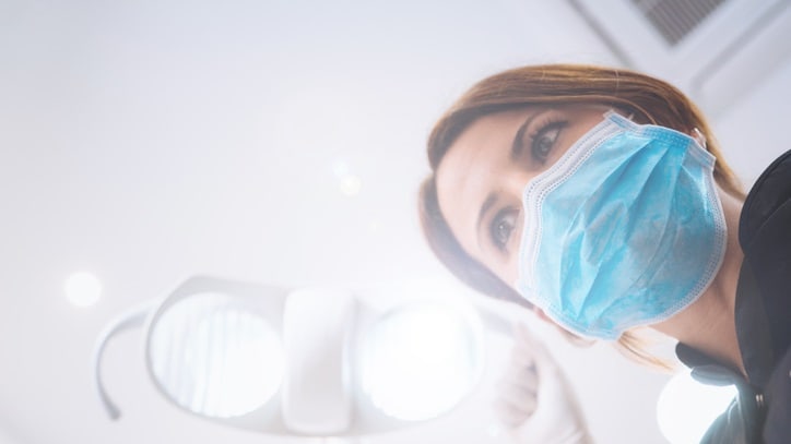 A woman wearing a surgical mask in a dental office.