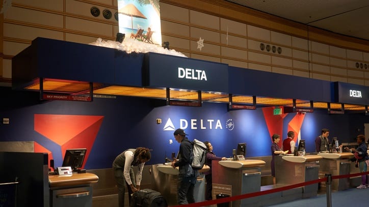 A group of people standing in line at a delta counter.