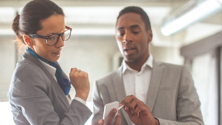 Two business people looking at a cell phone.