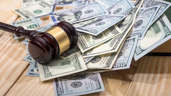 A judge's gavel on top of a stack of money.