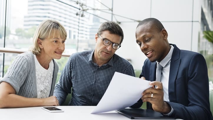 Three business people looking at a piece of paper.