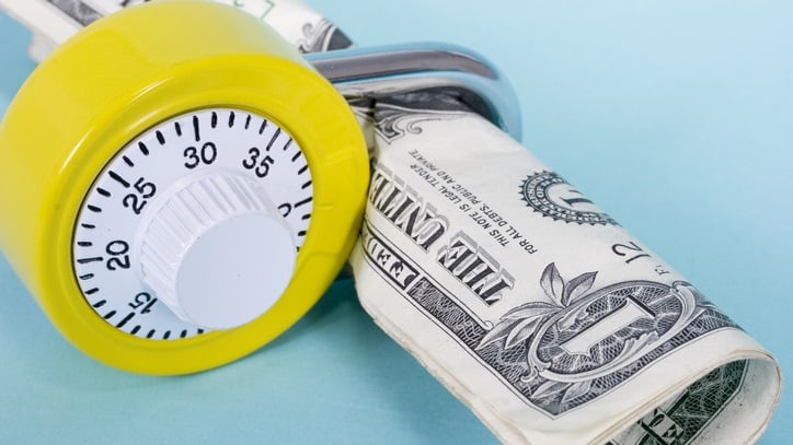 A yellow timer sitting on top of a stack of dollar bills.