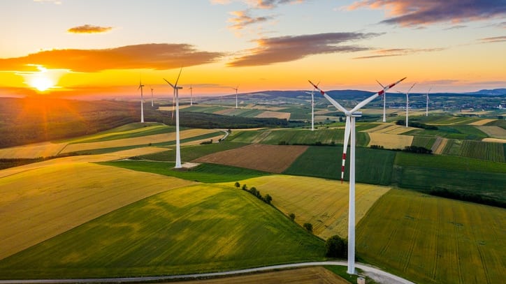 Aerial view of wind turbines in a field at sunset.