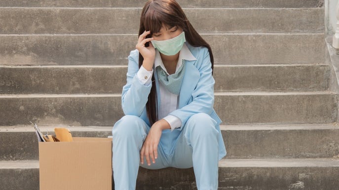 A woman in a surgical mask sitting on the steps.