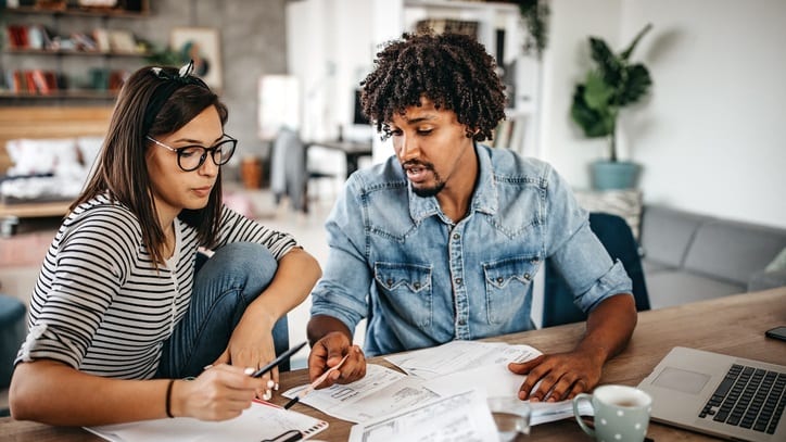 A couple working on a spreadsheet at a table in their home.