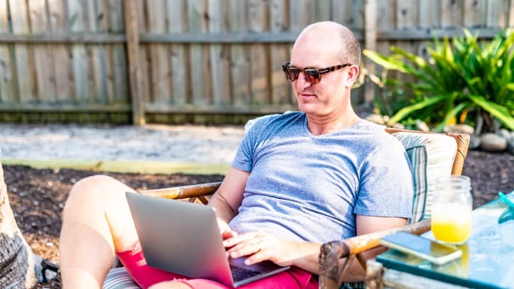 A man sitting in a lawn chair using a laptop.