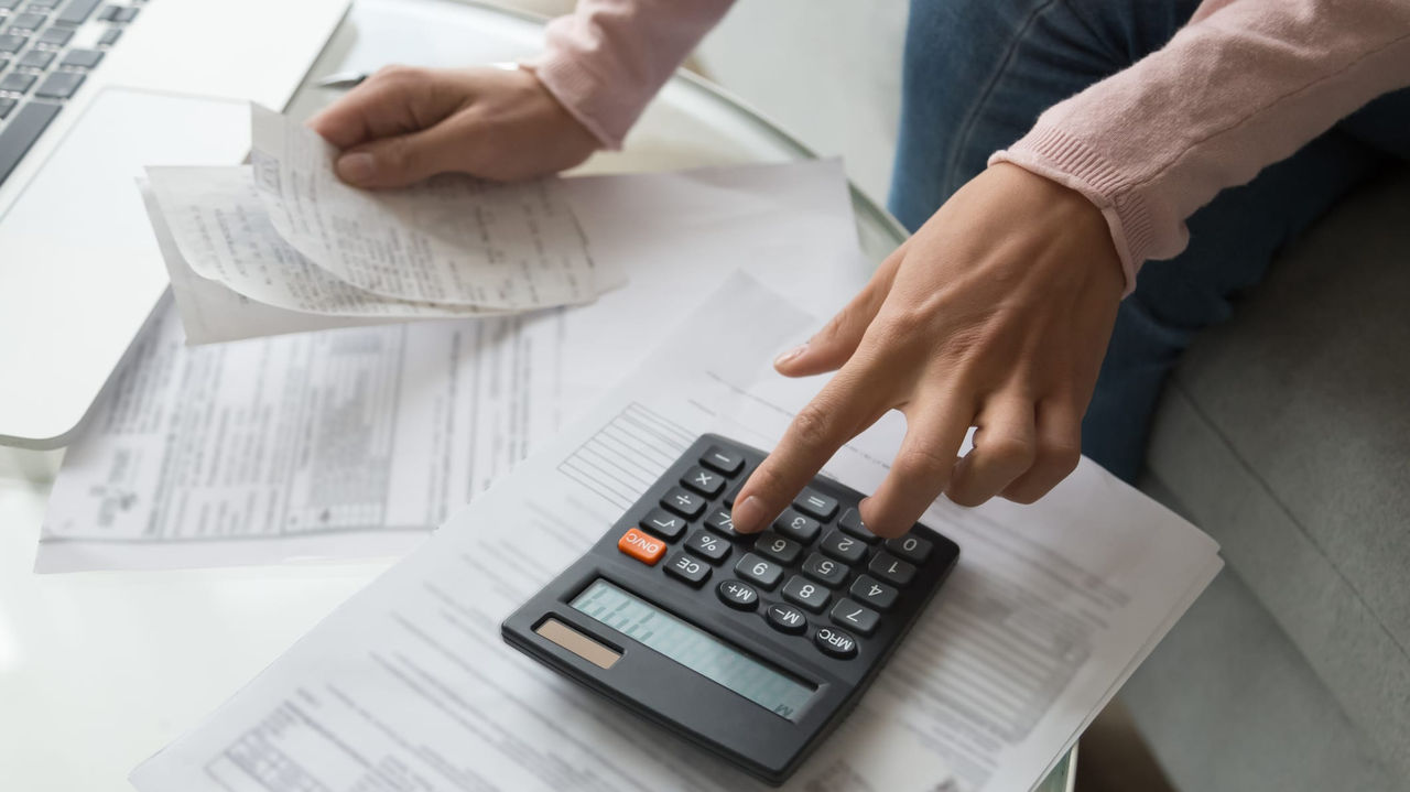 A woman using a calculator while sitting on a couch.