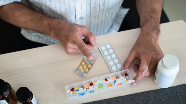 person selecting from a group of pills on a table
