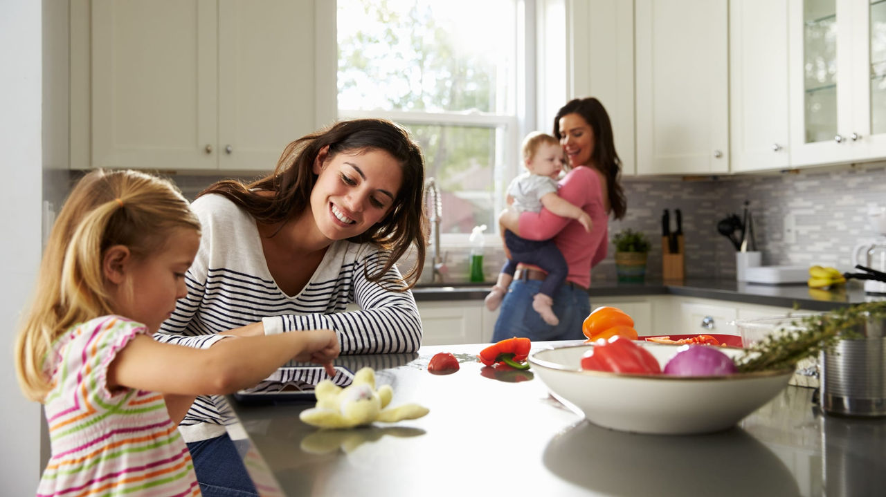 A woman and her daughter are preparing food in a kitchen.