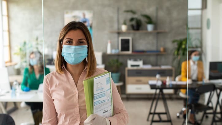 A woman wearing a surgical mask in an office.