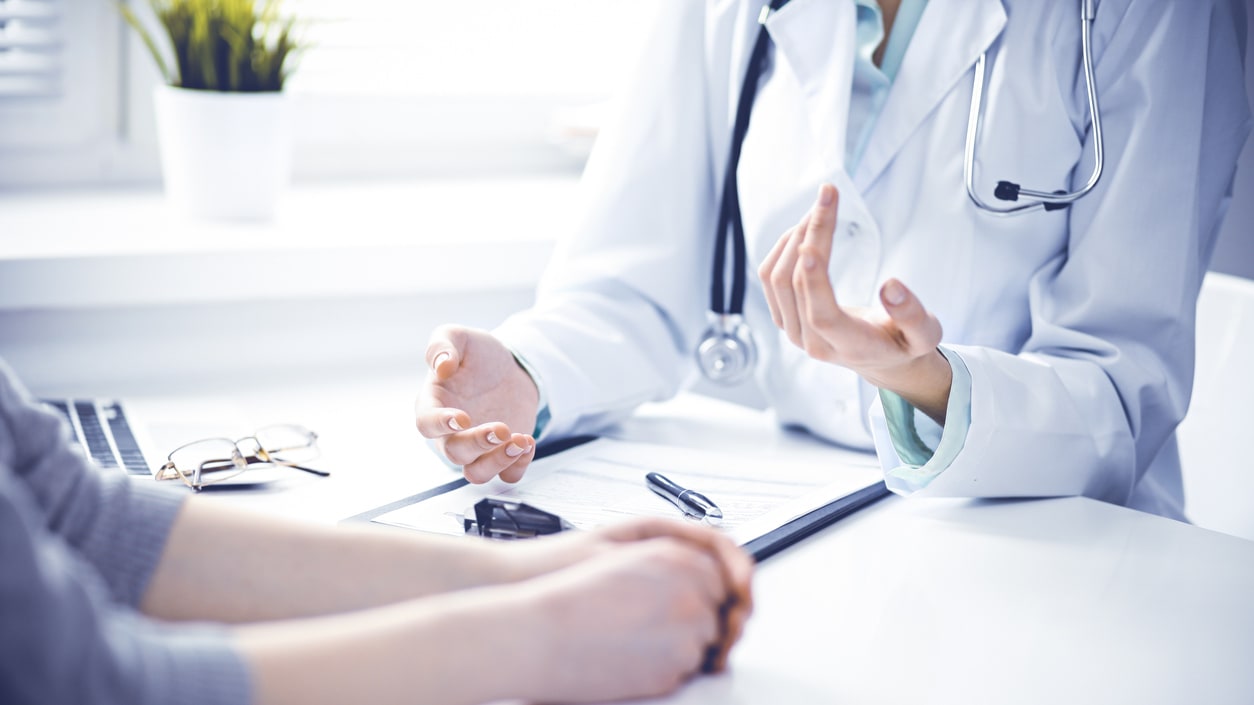 A doctor is talking to a patient at a desk.