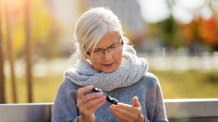 A woman is looking at her phone while sitting on a bench.