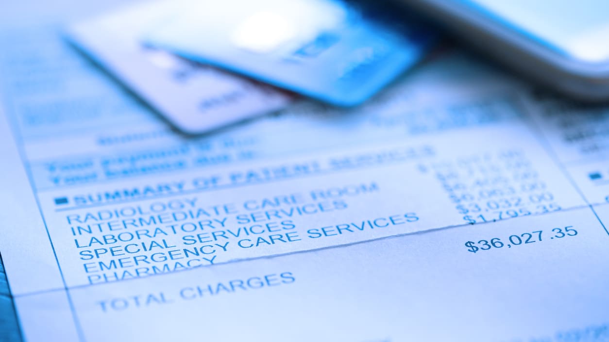 A cell phone and a credit card on top of a medical bill.