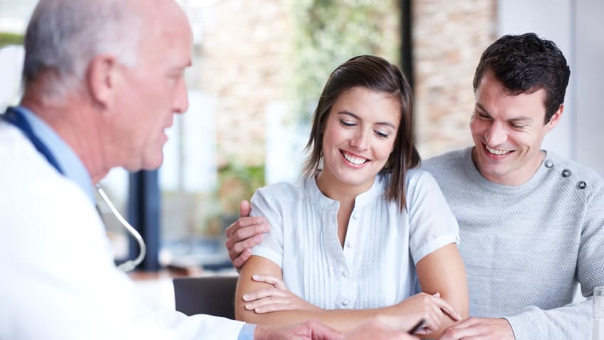 A man and woman sitting at a table with a doctor.