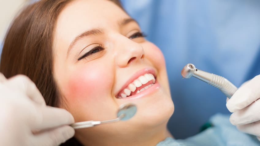 A woman is getting her teeth cleaned by a dentist.