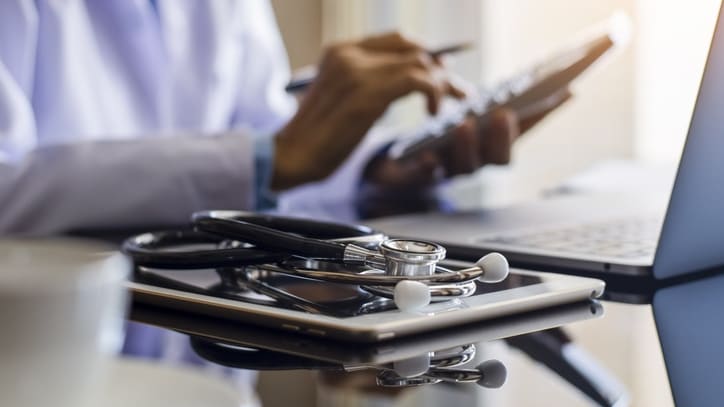 A doctor using a laptop and a stethoscope.