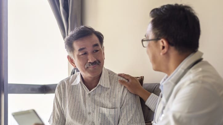 A doctor talking to a patient in a living room.