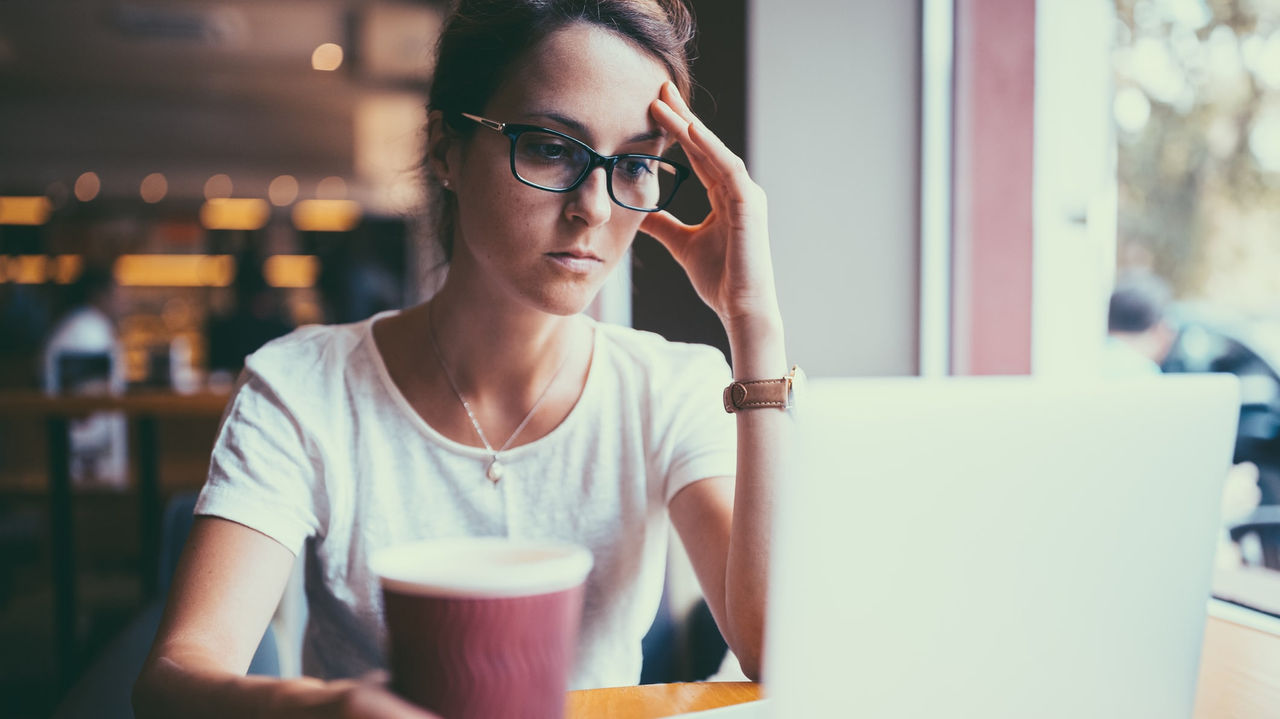 A woman sitting at a table with a cup of coffee and a laptop.