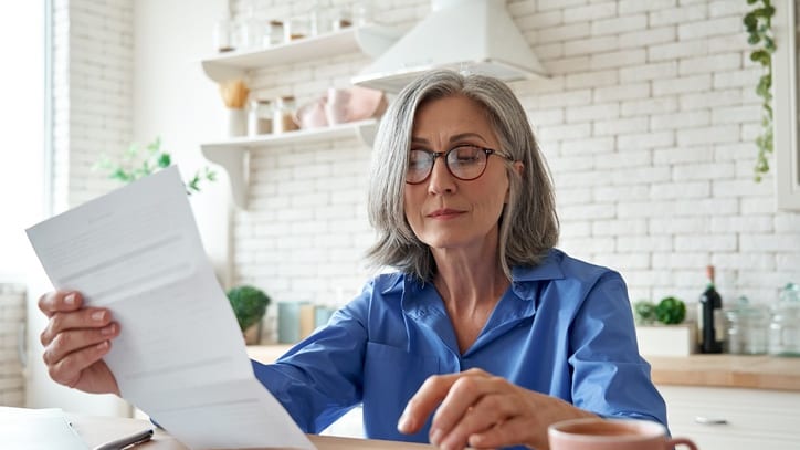 A woman is sitting at a table with a calculator and papers.