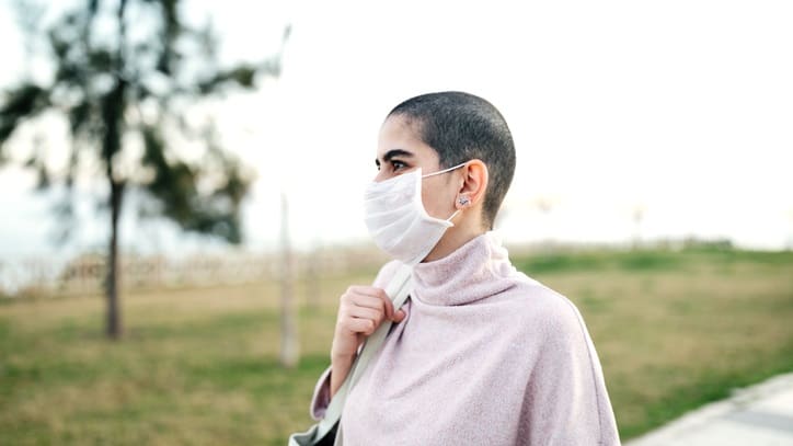 A woman wearing a face mask in a park.
