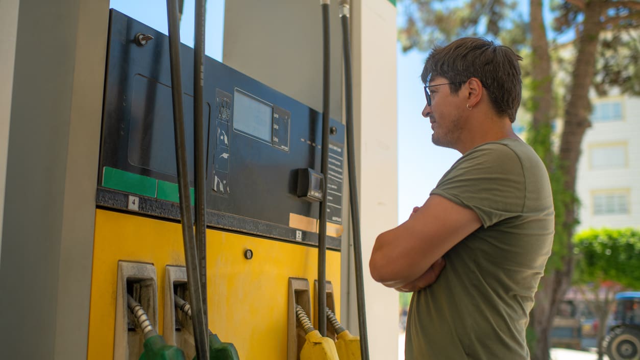 A man is standing at a gas station.