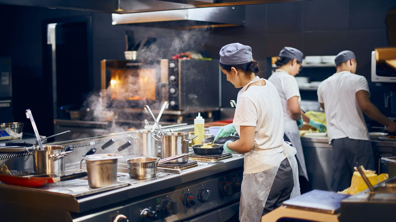 A group of people cooking in a commercial kitchen.