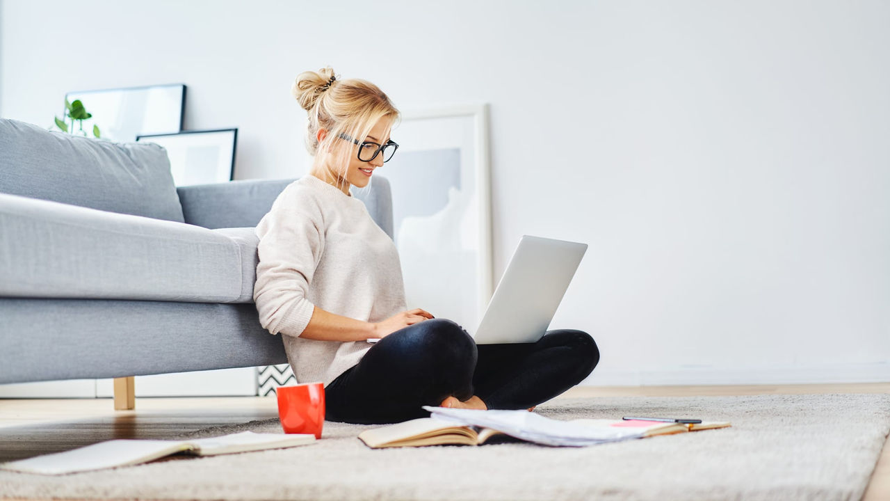 A young woman sitting on the floor with a laptop.