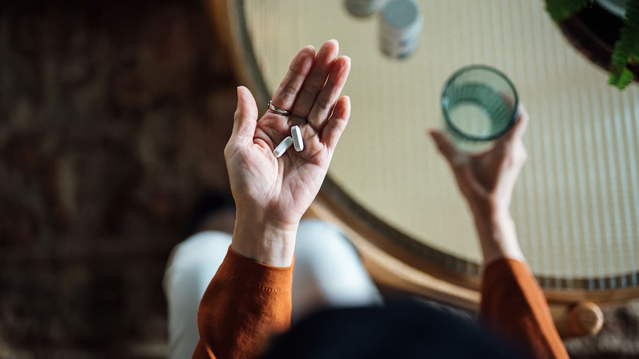 A woman holding a pill in her hand.