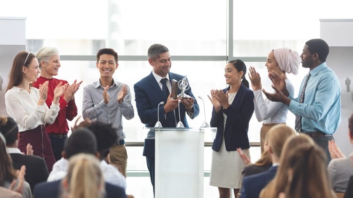 A group of business people applauding at an awards ceremony.