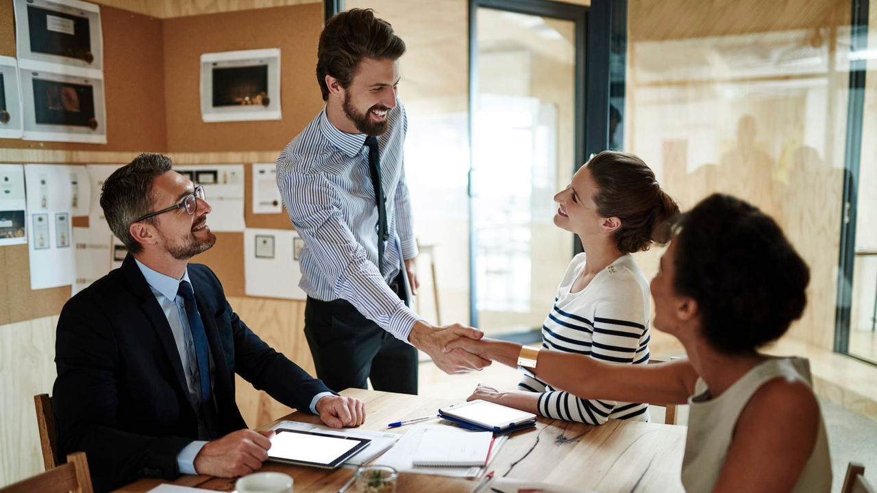 A group of business people shaking hands at a meeting.