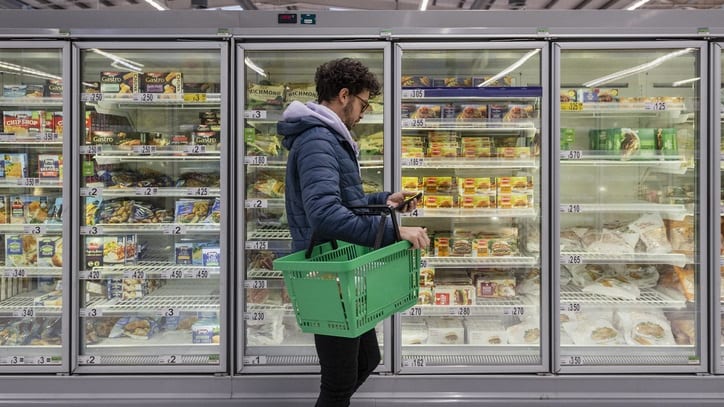 A man is standing in front of a fridge in a supermarket.