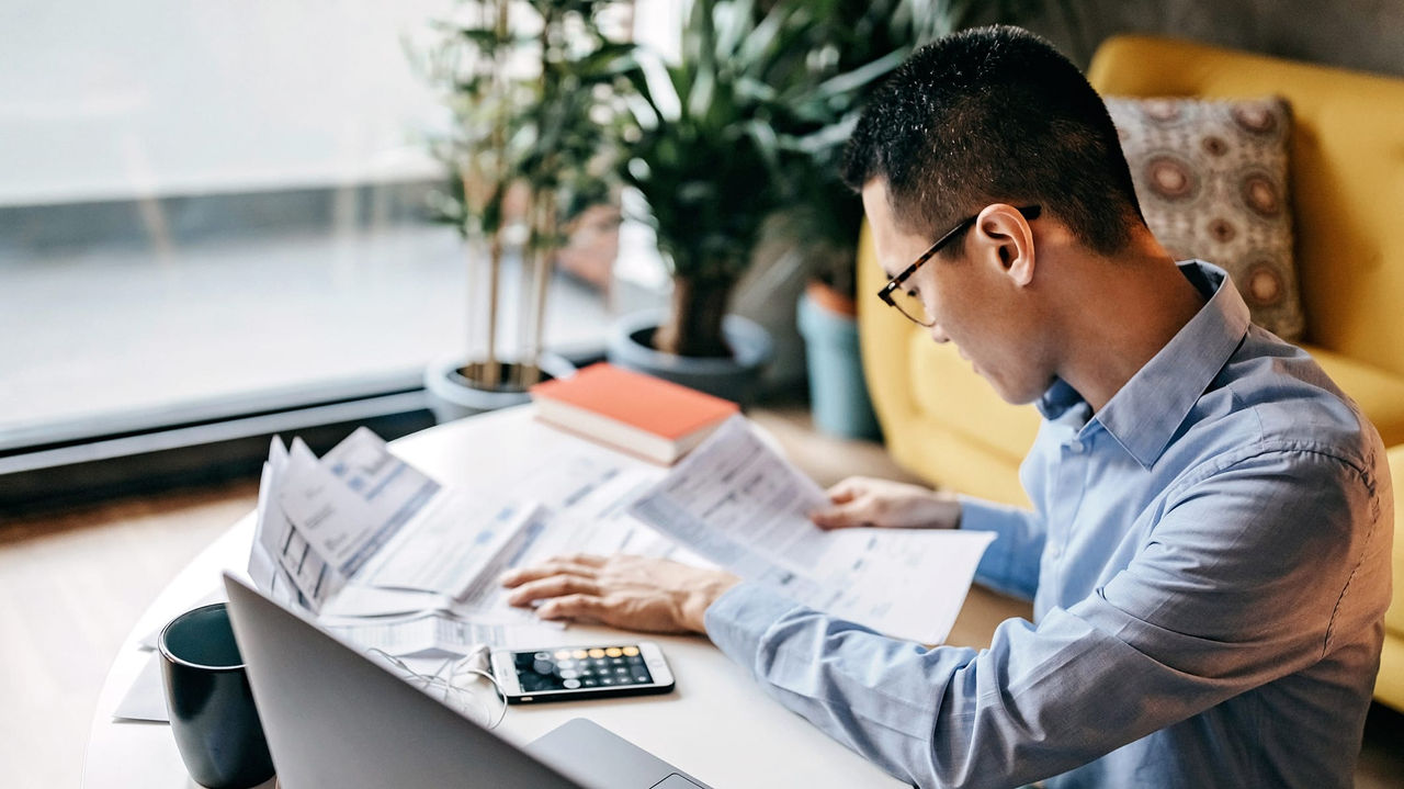 A man sitting at a table with papers and a laptop.