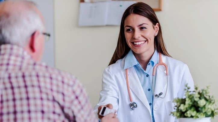 A doctor is talking to a patient at a desk.