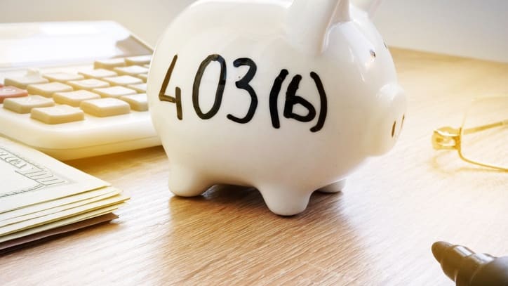 A piggy bank sitting on a desk next to a calculator.