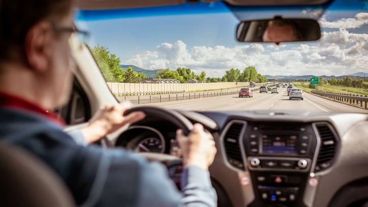 A man driving a car on a highway.